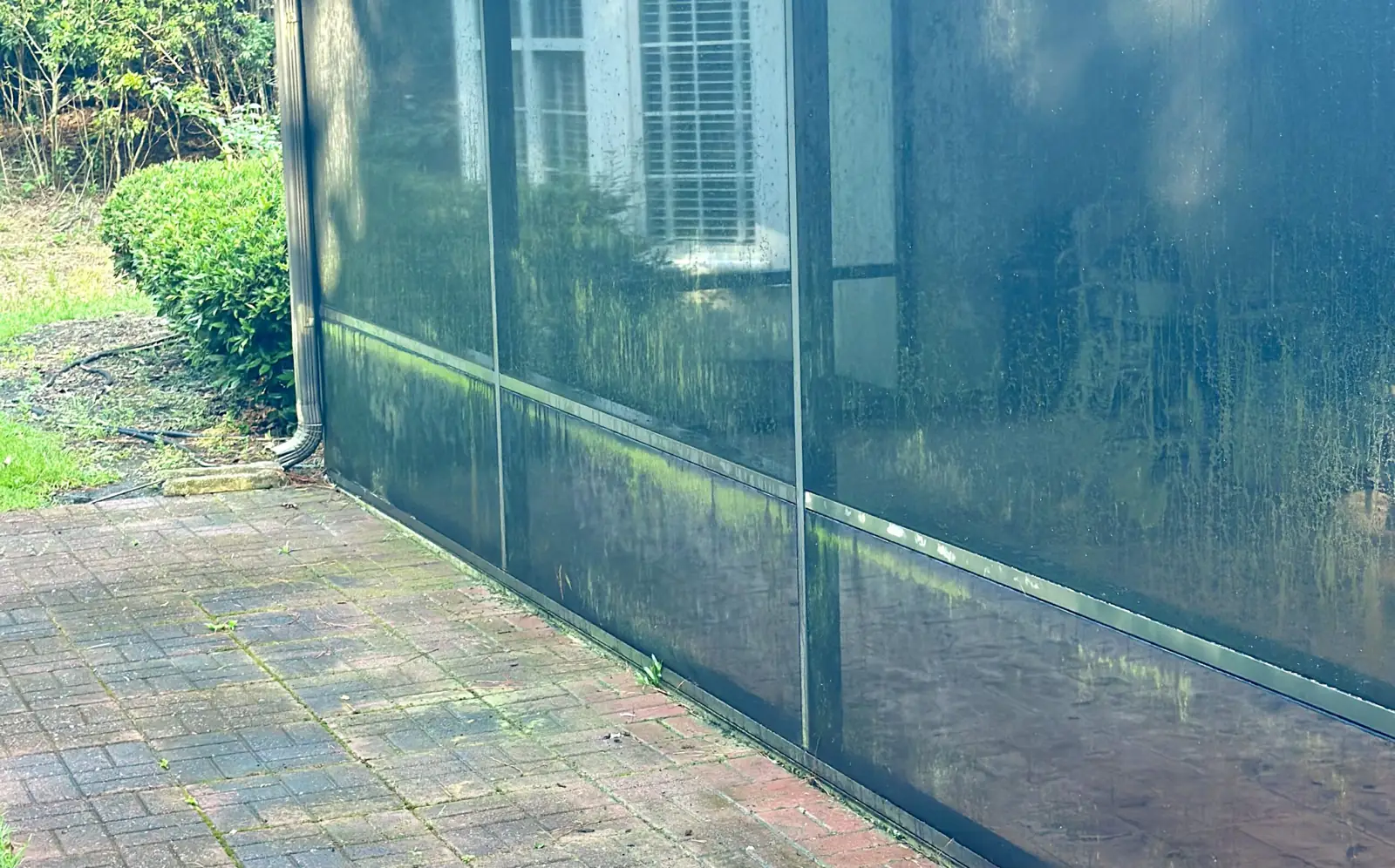 Mossy brick patio beside a screened porch before pressure washing in the Lowcountry